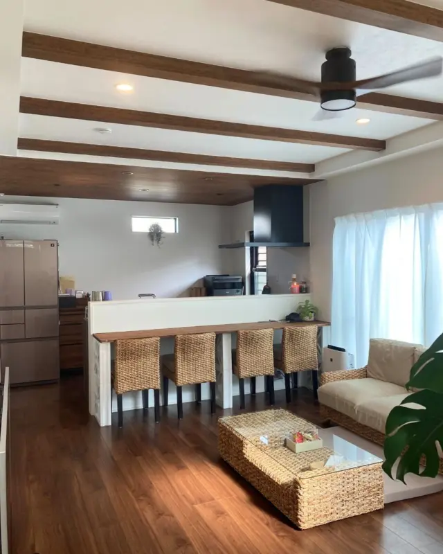 ｜素材感を楽しむリビングインテリア｜

ダークブラウンの床や天井梁に、ラタン素材の家具を組み合わせたLDK。
異素材をミックスしながらも、色のトーンを揃えることで落ち着きのある空間に仕上がっています。
天井にはファンを設け、室内の空気がやわらかく循環する設計に。
自然素材とモダンなラインが共存する、くつろぎやすい住まいの中心です。

---------------------------------------------
 
〜お客様がご満足いくまで寄り添い続ける〜
☆沖縄で木造住宅ならレキオホーム
☆創業52周年で導いた最高の住まいを一緒に
@taikyou_kensetu プロフィールURLからご覧ください！
 
お問い合わせは、お電話・HPお問い合わせフォームからお気軽に^ ^
 
---------------------------------------------
 
*対応エリア*
#沖縄本島全域
#中頭郡読谷村 #読谷村 #那覇市 #沖縄市 #うるま市 #浦添市 #宜野湾市 #豊見城市 #国頭郡 #名護市
 
*特徴*
#木造住宅 #木の家 #無垢の木 #住宅性能 #高性能 #補助金 #住宅ローン #ローン審査 #家事ラク #家事動線 #オシャレ新築 
 
*サービス*
#新築 #戸建 #注文住宅 #リノベーション #マンションリノベーション #古民家リノベーション